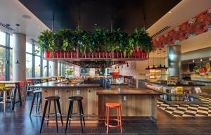 a restaurant with bar stools and potted plants at citizenM Menlo Park in Menlo Park