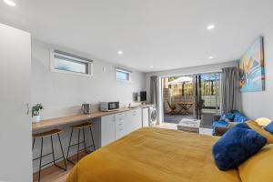 a bedroom with a bed and a kitchen with a counter at Dee Lightful - Mount Maunganui Holiday Home in Mount Maunganui