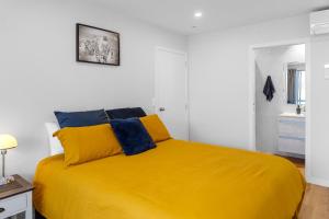 a yellow bed in a white room with a yellow blanket at Dee Lightful - Mount Maunganui Holiday Home in Mount Maunganui