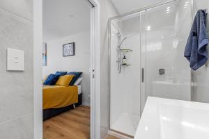 a bathroom with a shower and a bed in a room at Dee Lightful - Mount Maunganui Holiday Home in Mount Maunganui