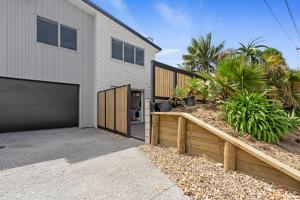 a house with a garage and a fence at Dee Lightful - Mount Maunganui Holiday Home in Mount Maunganui