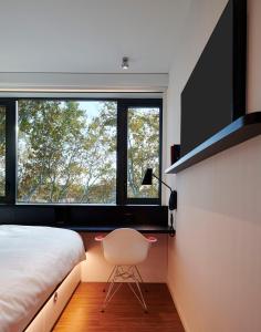 um quarto com uma cama, uma cadeira e uma janela em citizenM Rome Isola Tiberina em Roma