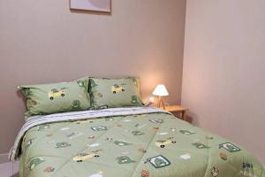 a bedroom with a bed with a green comforter at Shmawai Homestay Kota Tinggi in Kota Tinggi