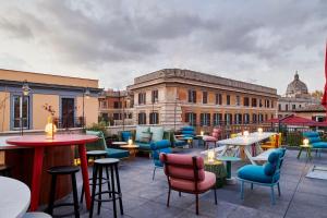 un patio avec des tables et des chaises et un bâtiment dans l'établissement citizenM Rome Isola Tiberina, à Rome
