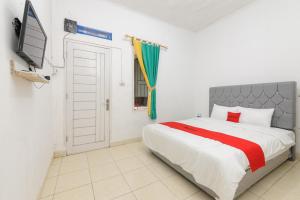1 dormitorio con 1 cama grande y TV en RedDoorz Syariah near Institut Darmajaya Lampung, en Bandar Lampung