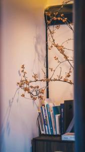 una mensola con libri e un ramo di Yangzhou Aihehua Boutique Homestay a Yangzhou