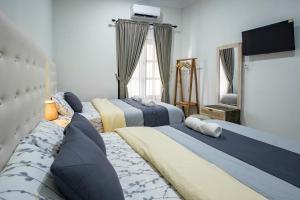 a bedroom with three beds and a flat screen tv at Bisma Balcony Homestay in Jetis