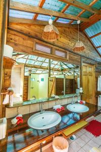 La salle de bains est pourvue de 2 lavabos et d'un grand miroir. dans l'établissement Heimanarii,slodge Manu, à Haapiti