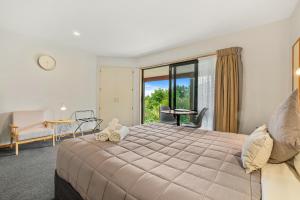 a bedroom with a large bed and a balcony at Alpine Garden Motel in Hanmer Springs