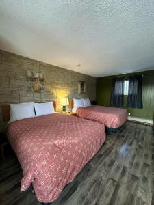 two beds in a hotel room with red sheets at Town and Country Motel in Nipigon