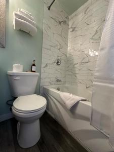 La salle de bains est pourvue de toilettes, d'une baignoire et d'un lavabo. dans l'établissement Town and Country Motel, à Nipigon