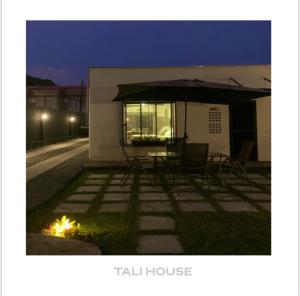 a house with a table and chairs and an umbrella at TALI HOUSE - Casa Hotel in São Francisco do Sul