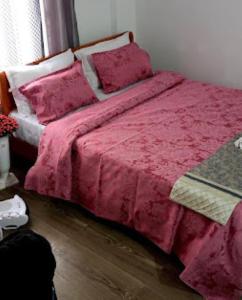 ein Bett mit einer rosa Bettdecke in einem Schlafzimmer in der Unterkunft Hotel Comfy Stay Tawang in Tawang