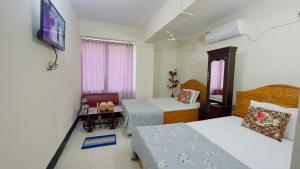 a bedroom with two beds and a tv on the wall at Hotel Royal Blue Residence in Dhaka
