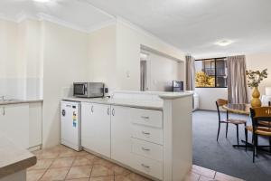 uma cozinha com armários brancos e uma mesa em Riverside Elegance Central 1BR 1BA Apartment em Perth