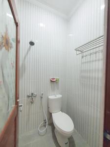 a white bathroom with a toilet and a shower at Kos Harian Wisma Selma Garuda in Kejayan