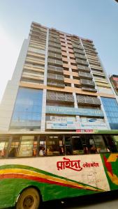 um autocarro estacionado em frente a um edifício alto em Hotel Royal Blue Residence em Daca