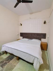 a bedroom with a large bed with white sheets at Nest Home Stay in Khajurāho