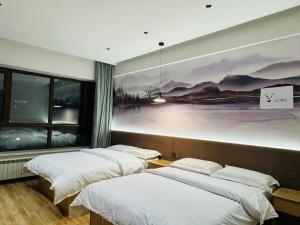 two beds in a room with a painting on the wall at Utopia Apartment in Harbin