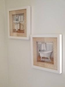 two framed pictures on a wall with a bath tub at Nice and cozy. Sleeps 5. in Chicago