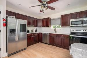 una cocina con armarios de madera y electrodomésticos de acero inoxidable en Abbey House, en Massapequa