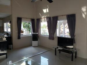 a living room with two windows and a flat screen tv at Luxury Private Pool Villa 5 min from Walking Street and Beaches in Pattaya South