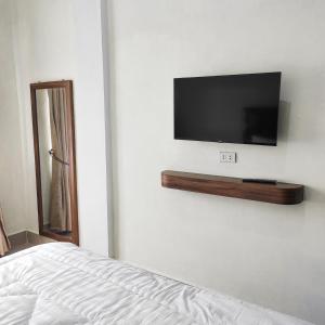 Kala Guest House في Kabanjahe: غرفة نوم مع تلفزيون على جدار أبيض