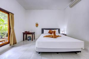 een slaapkamer met een wit bed en een raam bij Ari La Casa in Nusa Penida