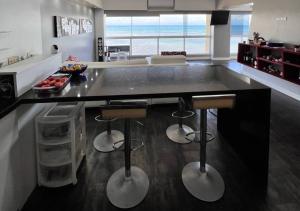 uma cozinha com um balcão preto com dois bancos de bar em Suite Coco CarIbe em Porlamar
