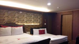 a hotel room with two beds and a headboard at Residence R Hotel in Daegu