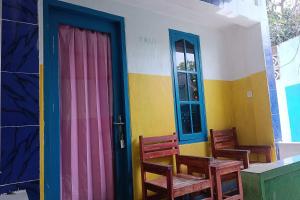 OYO 93359 Kawi Homestay في برايا: غرفة بها كرسيين وباب ملون
