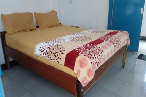 OYO 93359 Kawi Homestay في برايا: سرير بإطار خشبي وعليه بطانيه