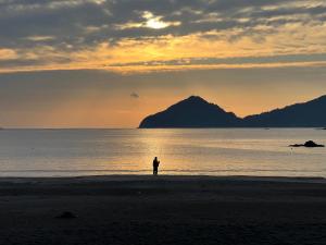 a person standing on the beach at sunset at サンライズ日南 in Nichinan