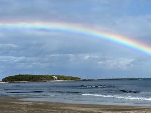 a rainbow in the sky over a beach at サンライズ日南 in Nichinan
