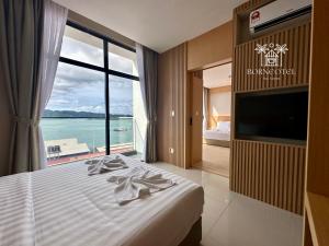 a bedroom with a bed with a view of the ocean at Borneotel The Shore KK by CHG in Kota Kinabalu