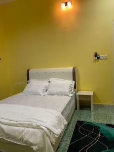 Bett mit weißer Bettwäsche und Kissen in einem Zimmer in der Unterkunft HOMESTAY Teratak Besut (HA) in Kampung Raja