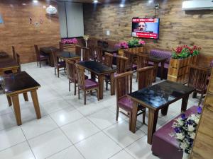 una sala da pranzo con tavoli, sedie e TV di Homewood Suites And Guest House a Jammu