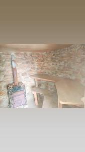 a table and bench in a room with a stone wall at Sunset Beach Bungalow Koh Pu in Ko Jum