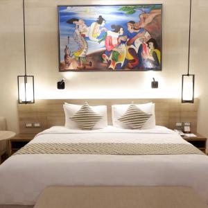 a bedroom with a bed with a painting on the wall at The Margaux Hotel Yogyakarta in Yogyakarta