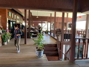 a woman walking through a restaurant with a plant at Aya House in Pai