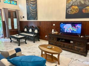een woonkamer met een flatscreen-tv op een entertainmentcentrum bij AW Griya Semilir in Timuran