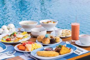 una mesa con platos de comida en una mesa junto al agua en Homm Suites Laguna, en Bang Tao Beach