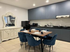uma cozinha com uma mesa de madeira e cadeiras azuis em Reizz Residence by Perkasa em Kuala Lumpur