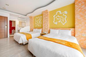 墾丁的住宿－圍園旅店，两张床位于带黄色墙壁的酒店客房