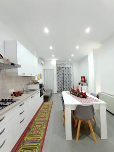 uma cozinha com armários brancos e uma mesa com cadeiras em Casa vacanze Sicilia bedda partinico em Partinico
