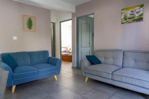 una sala de estar con 2 sofás azules y una puerta en Appart Maïté 4, en La Saline-Les-Bains