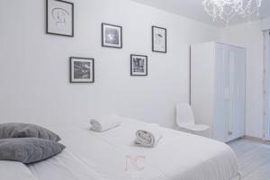 a white bedroom with a bed and some pictures on the wall at *Disneyland-Paris* 4pers, Parking, Wifi in Chessy