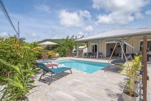 una piscina con sillas y una casa en Villa BelRock, en Le Diamant