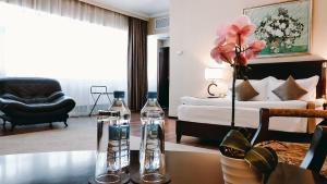 a living room with a bed and a table with two bottles at REIKARTZ PARK ASTANA ex-Royal Park Hotel & SPA in Astana