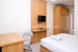 a bedroom with a bed and a desk and a tv at Garuda Guesthouse Yogyakarta RedPartner in Yogyakarta